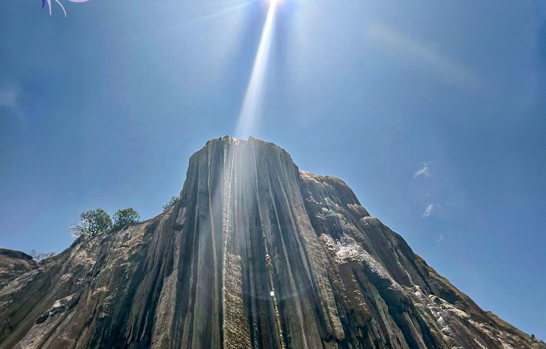 The petrified waterfall of Hierve el Agua seen from below, with the sun above